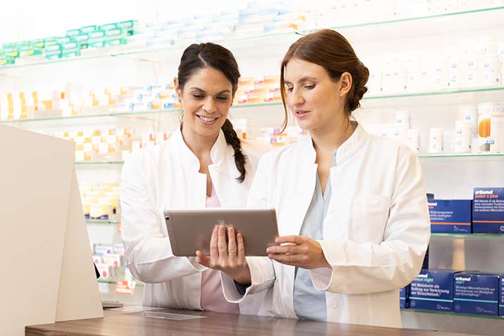 Zwei junge Apothekerinnen arbeiten an einem Tablet.
