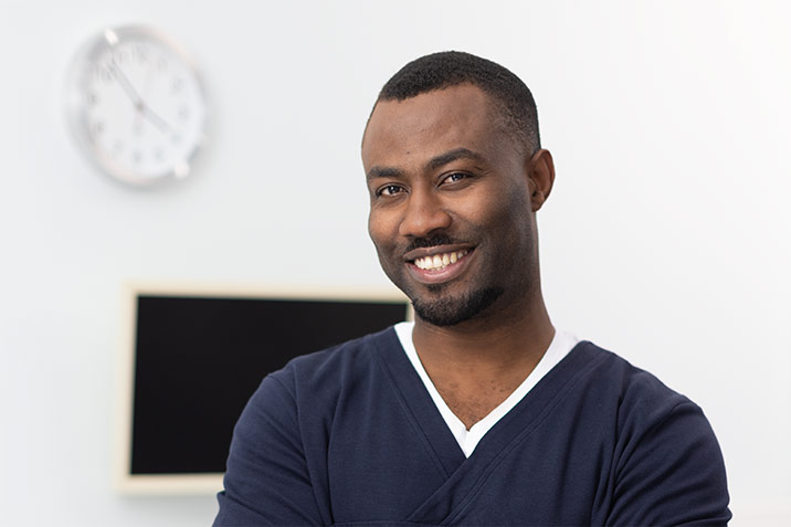 Ein junger Arzt lächelt in die Kamera.